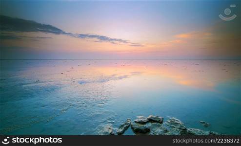 Tranquil and tranquil zen-like sunset on the beach with beautiful colors in pink and red with reflections on the water - Wadden Sea, Netherlands. Reflecting mudflats all twilight with setting sun