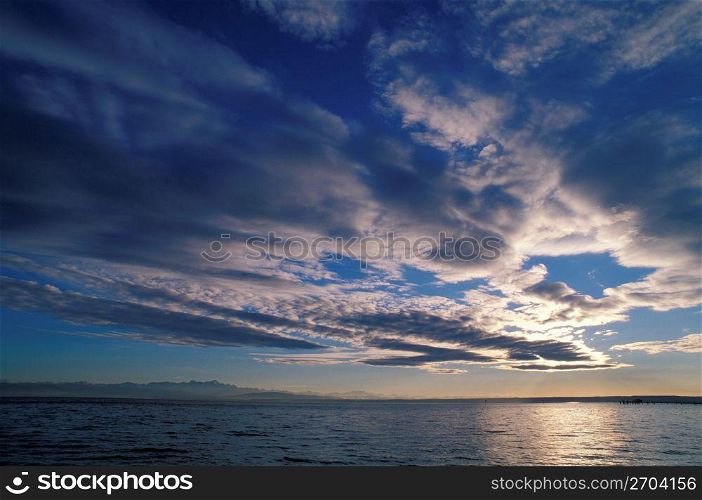 Tranquil blue sky and clouds over ocean with land in distance