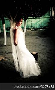 Tranquil bride in wedding dress leaning against post daydreaming