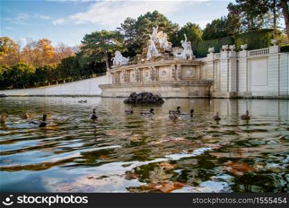 Tranquil fall landscape from monument with ancient statues and pond with floating ducks in a park near Schonbrunn Palace in Vienna, Austria. Monument with ancient statues and pond with floating ducks in Vienna.