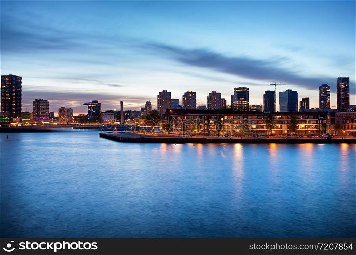 Tranquil river view of the Rotterdam city centre in Holland, Netherlands at dusk.