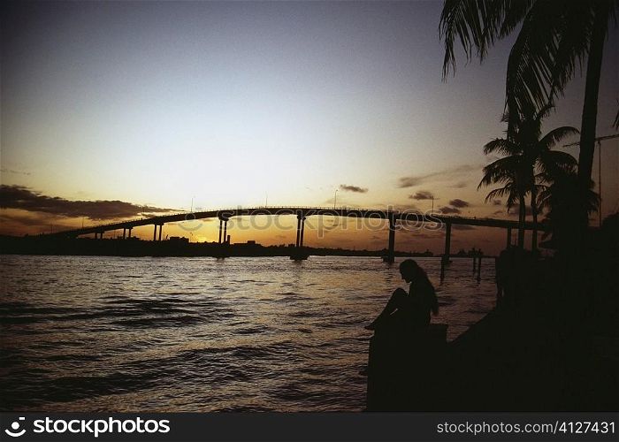 Tranquil seascape and a bridge silhouetted against the sky at sunset, Grand Bahamas, Bahamas