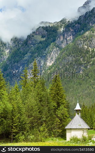 Tranquil summer Italian dolomites mountain village old chapel view.