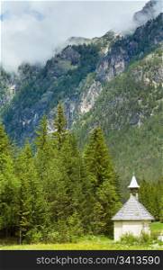 Tranquil summer Italian dolomites mountain village old chapel view.