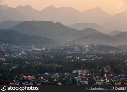 Tranquil view of Luang Prabang ancient town surrounded by mountains at dusk, a travel destination in Laos and Southeast Asia. UNESCO World Heritage Site.