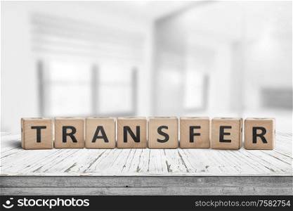 Transfer sign on a wooden table in a bright offce with windows in the background