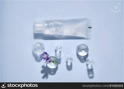 Transparent bottle of cosmetic gel on a blue background with small bottles of water. Suitable for advertising shower gel, shampoo and other care products.. Transparent bottle of cosmetic gel on a blue background with small bottles of water.