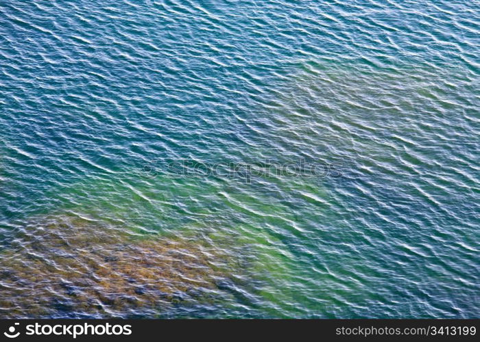 transparent coastal azure water surface with some stones on bottom