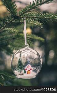 Transparent cristalball with christmas tree and house inside. Snow in christmas ball.