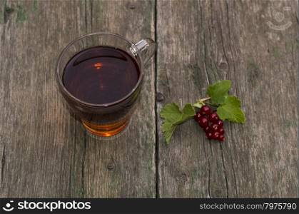 transparent cup of tea and branch of red currant on a shabby table, top view, a subject summer berries