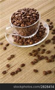 Transparent cup with coffee grains on a background of a mat