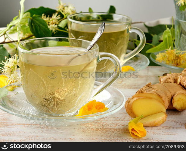 transparent cup with tea from ginger and linden on a white wooden board