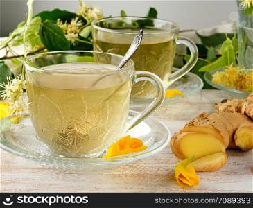 transparent cup with tea from ginger and linden on a white wooden board