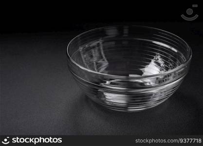 Transparent glass bowl as an element of kitchen utensils for cooking at home on a dark concrete background