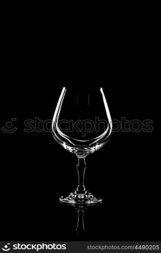 transparent glass for brandy or cognac on black background with reflection