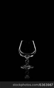 transparent glass for brandy or cognac on black background with reflection