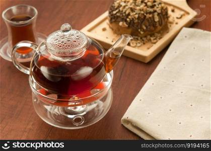 Transparent glass teapot and cup with tea on lerevyannoy surface brown and cookies on the board. Transparent glass teapot and cup with tea
