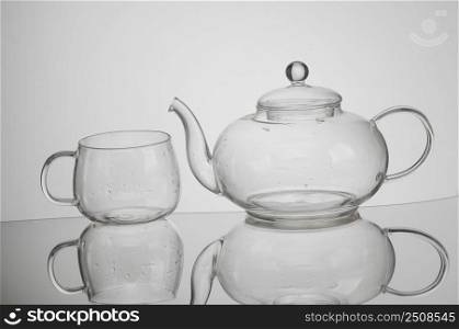 transparent glass teapot and tea cup with reflection. kitchen transparent kettle