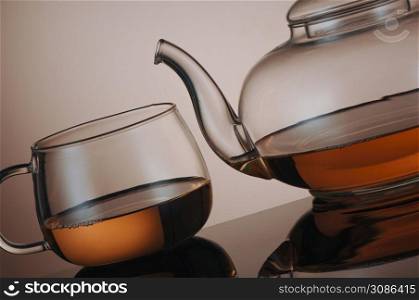 transparent glass teapot and tea cup with reflection. kitchen transparent kettle