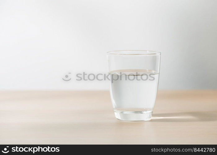Transparent glass with water on a wooden table in the room. Drinking clear water in the morning for health.