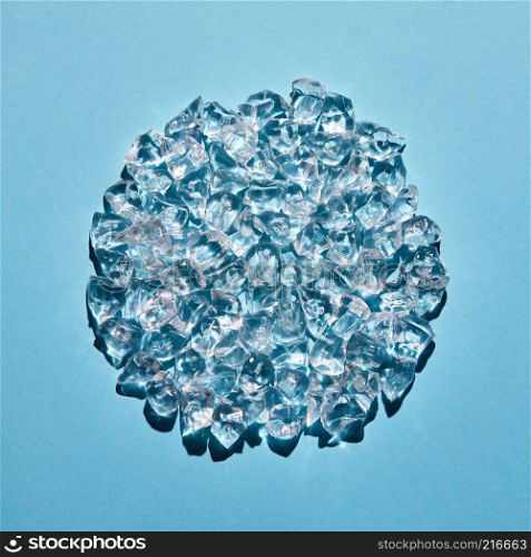 Transparent ice cubes in the shape of a circle on a blue background. Refreshing background for your ideas. A circle made of transparent ice cubes on a blue background