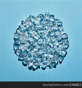 Transparent ice cubes in the shape of a circle on a blue background. Refreshing background for your ideas. A circle made of transparent ice cubes on a blue background