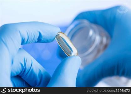 Transparent liquid supplement in capsule in scientist hands