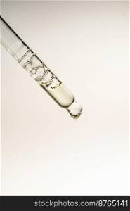 Transparent pipette with bubbles of oil or serum on a beige background. A great photo for your cosmetics business.. Pipette with bubbles on a green background.