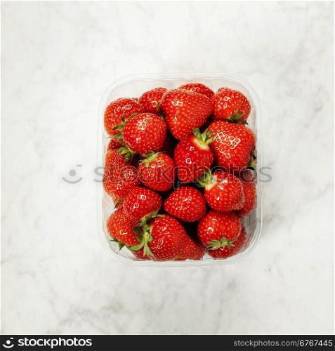 Transparent plastic tray with freshly picked strawberries