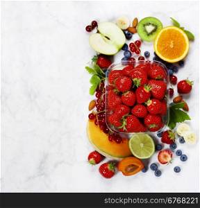 Transparent plastic tray with freshly picked strawberries and fresh fruits