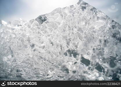 Transparent shining clear ice icicles close-up sparkling on frozen wild lake shore in sunset light. Cold winter nature background. Stacks of drift ice piled up against the dutch coast with crystal clear sunlight