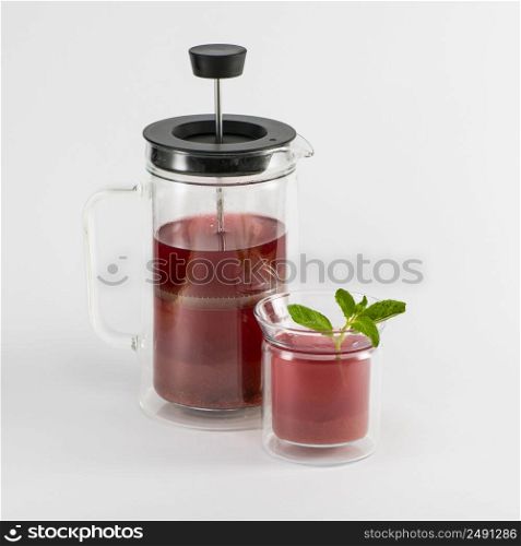 transparent teapot with fruit drink and glass with mint on white background, isolated. piston teapot. tea drink on white background
