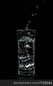 transparent water glass with ice cubes on black isolated glass background