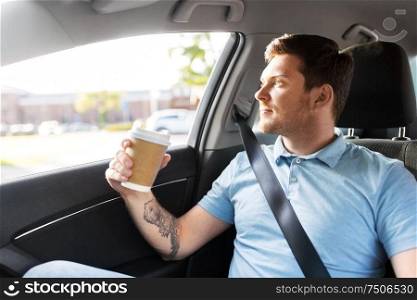 transport and people concept - man drinking takeaway coffee on back seat of taxi car. man with takeaway coffee on back seat of taxi car