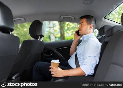 transport, business and communication concept - businessman drinking takeaway coffee and calling on smartphone on back seat of taxi car. businessman with coffee calling on phone in car