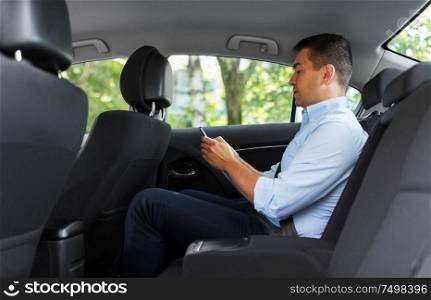 transport, business and communication concept - male passenger or businessman using smartphone on back seat of taxi car. passenger or businessman using smartphone in car
