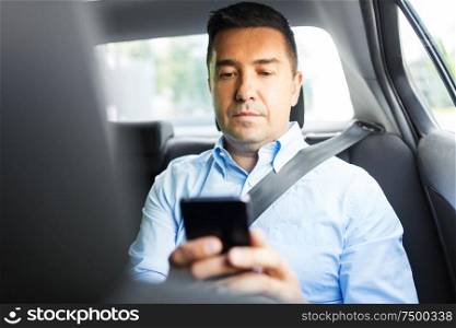 transport, business and communication concept - male passenger or businessman using smartphone on back seat of taxi car. passenger or businessman using smartphone in car