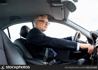 transport, business trip and people concept - happy senior businessman starting car and driving