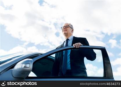 transport, business trip and people concept - senior businessman getting into car