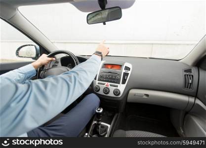 transport, business trip, direction and people concept - close up of young man driving car and pointing finger to something
