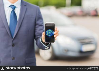 transport, business trip, ecology, technology and people concept - close up of man showing smartphone eco mode icon on screen on car parking