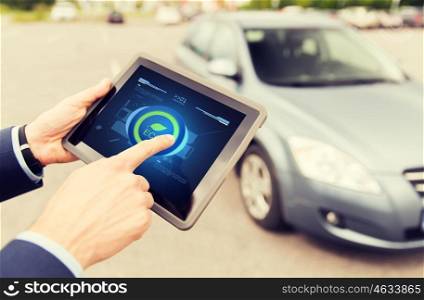 transport, business trip, technology and people concept - close up of male hands setting eco driving mode on tablet pc computer and car outdoors