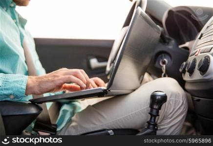transport, business trip, technology and people concept - close up of young man with laptop computer driving car