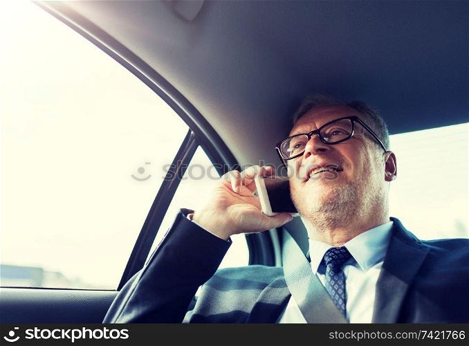 transport, business trip, technology and people concept - senior businessman calling on smartphone and driving on car back seat. senior businessman calling on smartphone in car