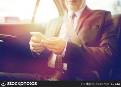 transport, business trip, technology and people concept - senior businessman texting on smartphone and driving on car back seat. senior businessman texting on smartphone in car