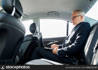 transport, business trip, technology and people concept - senior businessman with laptop computer driving on car back seat