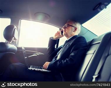 transport, business trip, technology and people concept - senior businessman with laptop computer calling on smartphone and driving on car back seat. senior businessman calling on smartphone in car