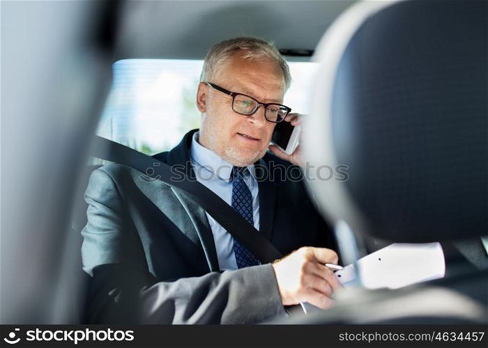 transport, business trip, technology and people concept - senior businessman with papers calling on smartphone and driving on car back seat