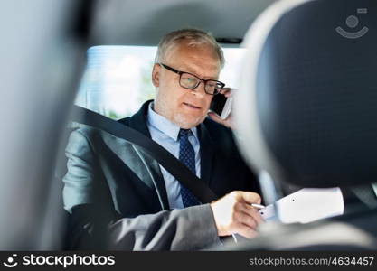 transport, business trip, technology and people concept - senior businessman with papers calling on smartphone and driving on car back seat