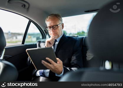 transport, business trip, technology and people concept - senior businessman with tablet pc computer driving on car back seat